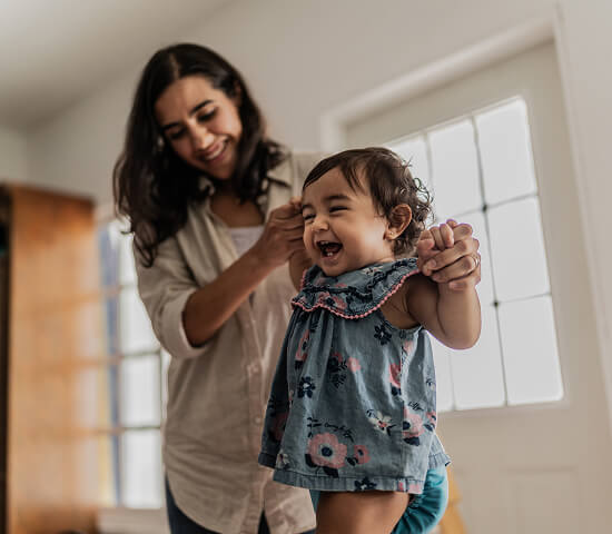 mom helping young daughter walk 