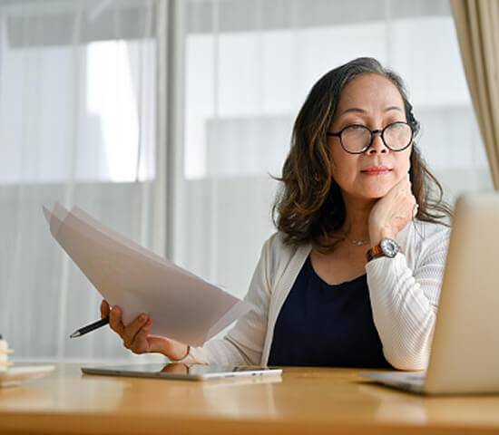 woman with documents in front of laptop 