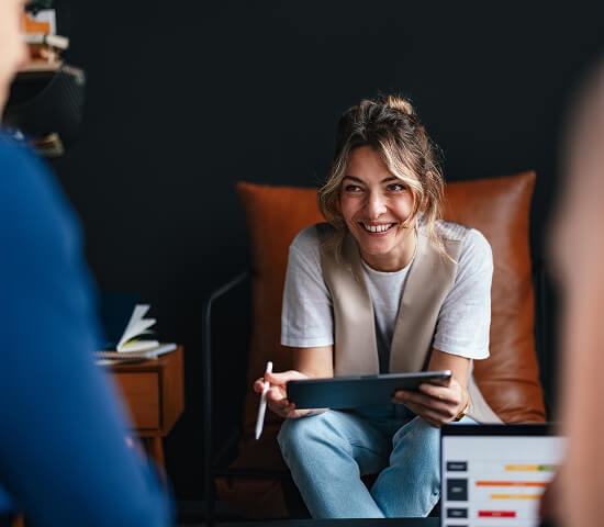 woman with tablet smiling at team members 