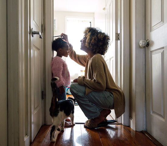mom measuring daughters height in door frame