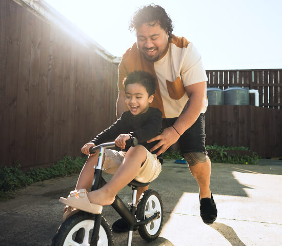 dad helping son ride a bike